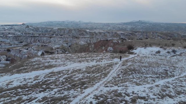 Aerial Landscape Of Woman Alone At Snow Covered Red Valley With Its Spectacular Volcanic Rock Formations In Cappadocia, Turkey.	