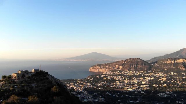 4K Drone Footage.  Everning drone flight towards a cross on a mountain top, with Sorrento below, and Mount Vesuvius in the background