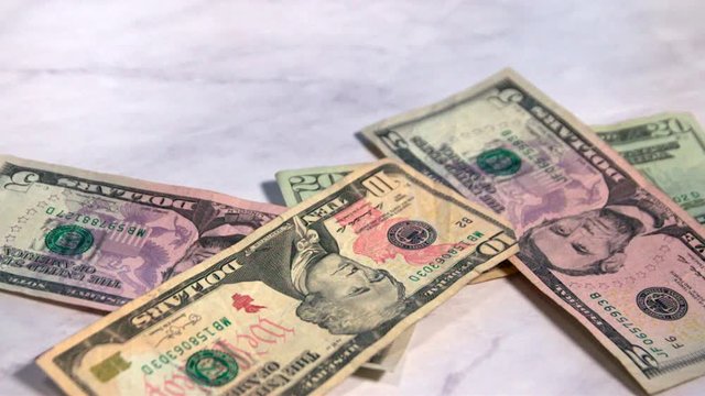 American money falling onto a marble countertop.