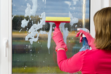 window cleaning. A woman in pink rubber gloves washes a window in a house. Happy Woman In Gloves...