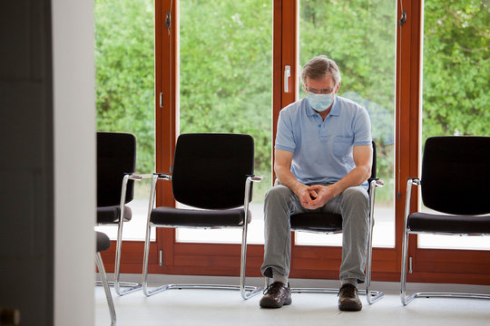 Mature Patient Or Visitor Sitting Alone In An Empty Waiting Room Of An Office Or Hospital