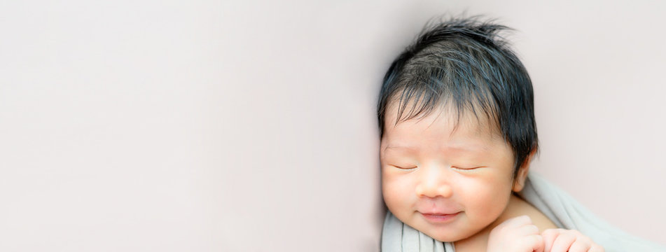 Panorama image of an adorable cute smiling Asian newborn baby sleeping