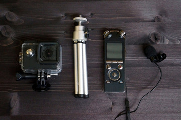 Portable camera, tripod, voice recorder and microphone. Equipment for blogging. Planning and preparing for an interview or video. View from above. Black table background.