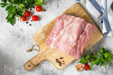 Raw pork carbonate on a wooden Board on the light gray kitchen table. Raw pork meat, tenderloin. The view from the top