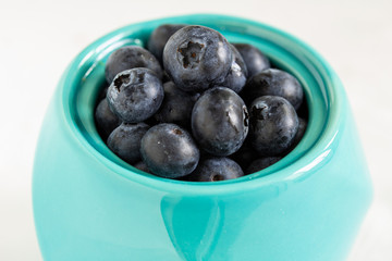 Blueberries in close-up in a birch pot on a light background