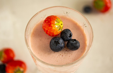 Dessert strawberry panna cotta in a glass wine glass decorated with a whole strawberry and blueberry