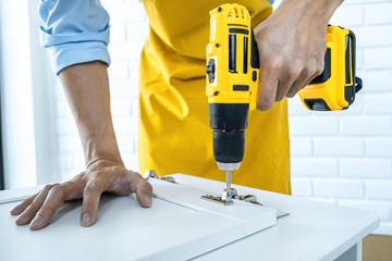 Man doing renovation work at home drilling wood with drill tack on locker