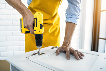 Man doing renovation work at home drilling wood with drill tack on locker