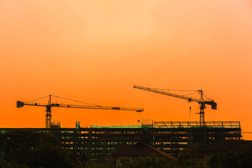 Silhouette tower crane and building on site Industrial construction on sunset background