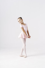 Delicate girl ballerina standing in ballet pose on white background in studio. Kinds personality development concept. - obrazy, fototapety, plakaty