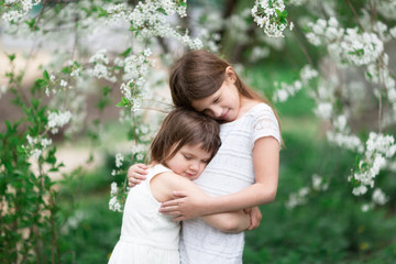 Tender children hugging near flowering tree
