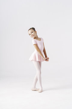 Delicate girl ballerina standing in ballet pose on white background in studio. Kinds personality development concept.