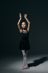 Fototapeta na wymiar Beautiful girl ballerina dancing in light play and shadowson dark background
