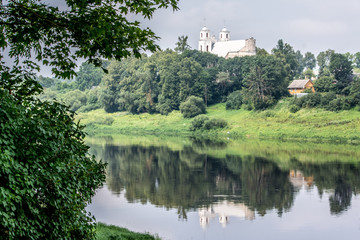 Fototapeta na wymiar river, on the banks of which there is a Catholic church, next to residential village houses