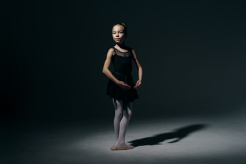 Fototapeta na wymiar Beautiful girl ballerina dancing in light play and shadowson dark background