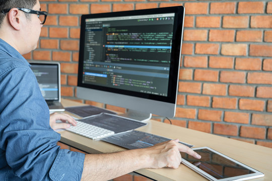 Young Professional programmer working at developing programming and website working in a software develop company office, writing codes and typing data code, Programming with HTML, PHP and javascript