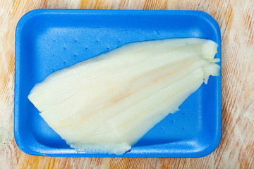 Raw seafood, fresh halibut fish on plastic blue plate
