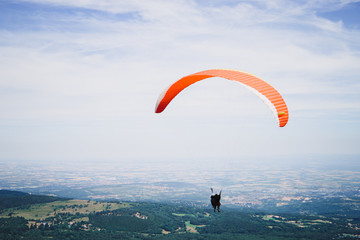 Silhouette of a landing skydiver against the sky. People are gliding using a parachute on the land...