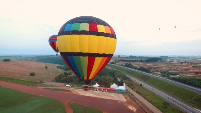 Aerial view with drone spinning around a colorful hot air balloon during a cloudy morning