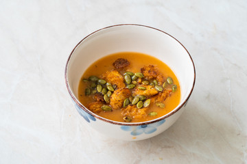 Homemade Butternut Squash Soup with Pumpkin Sauce, Pumpkin Seeds, Carrot and Crispy Croutons Bread.