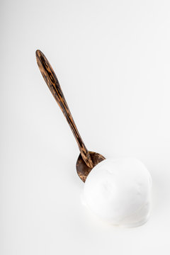 A Scoop Of Vanilla Ice Cream With A Brown Wooden Spoon