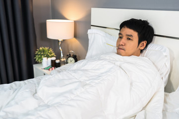sick man feeling cold and using thermometer to checking his temperature in bed