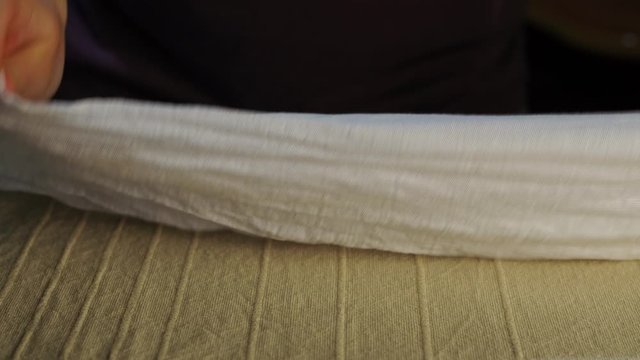 a man turns over a white pillowcase on an Ironing Board