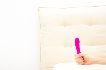 Female in bad holding a vibrator. Sex toy for adult