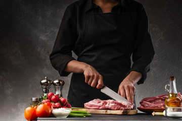 Slicing fresh pork ribs for frying on a background of vegetables. Cooking