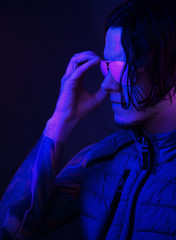 Man with long hair in sunglasses in neon retro wave light.