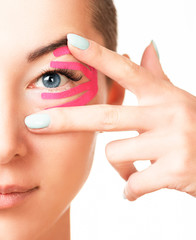 Half face portrait of woman with kinesiology tapes on eyelid against wrinkles.