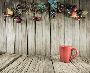 a red cup of coffee with Christmas ornament on the old wooden panel background.