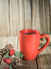Obraz na płótnie Canvas a red cup of coffee with Christmas ornament on the old wooden table top with wood panel background.