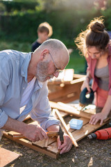 A man and his family are building wooden planters for their vegetable garden