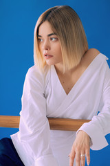 Naklejka premium Portrait of a pretty blonde woman in white shirt posing with wood stick