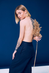 Obraz premium Portrait of a pretty blonde woman standing looking to the camera holding a wheat stalk 