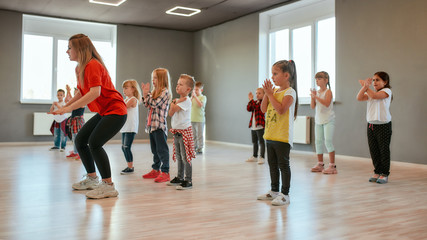 Group of little boys and girls dancing while having choreography class in the dance studio. Female...