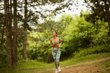 Young fitness woman running at forest trail