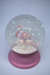 Crystal ball with pink base and glitter, filled with water and a pink flamingo on the bottom, decorations