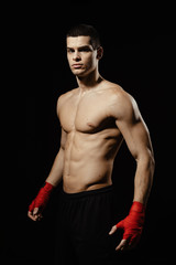 Fototapeta na wymiar Portrait of male boxer posing in boxing stance against black background.