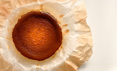 Top view of Basque burnt cheesecake on baking paper on white background.