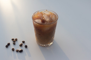 Cold coffee a cooling drink with ice in a glass cup on a light background.