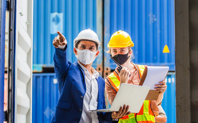Engineer and worker team wearing protection face mask against coronavirus, Foreman in hardhat and safety vest checking containers box from cargo, Teamwork concept