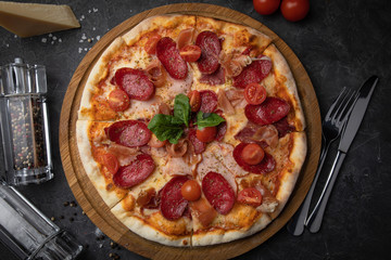 
Italian pizza with tomatoes salami, parma, meat and cheese on a black background