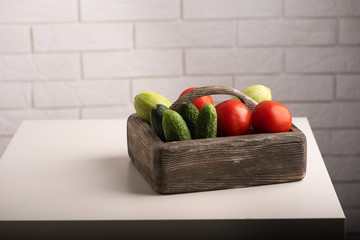 Cucumbers, tomatoes and zucchini in a wooden box on a table. Healthy food, raw vegetables concept