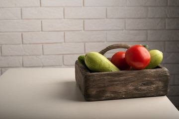 Cucumbers, tomatoes and zucchini in a wooden box on a table. Healthy food, raw vegetables concept