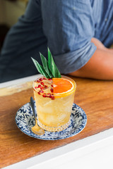 The orange fruity cocktail that mix with sliced orange and pomegranate pulps in a drinking glass. Decorated with banana leaves.