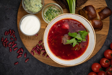 Ukrainian borsch with donuts, garlic, tomatoes on a black background
