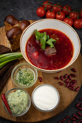 Ukrainian borsch with donuts, garlic, tomatoes on a black background
