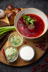 Ukrainian borsch with donuts, garlic, tomatoes on a black background
